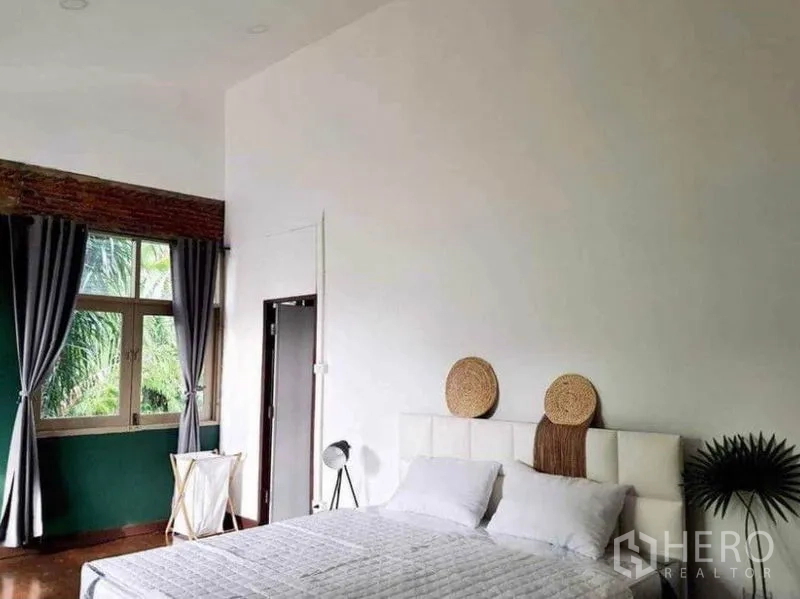 Detached House for rent in Pathum Wan, Bangkok - Bright bedroom with white headboard, high ceiling and curtained window overlooking greenery.