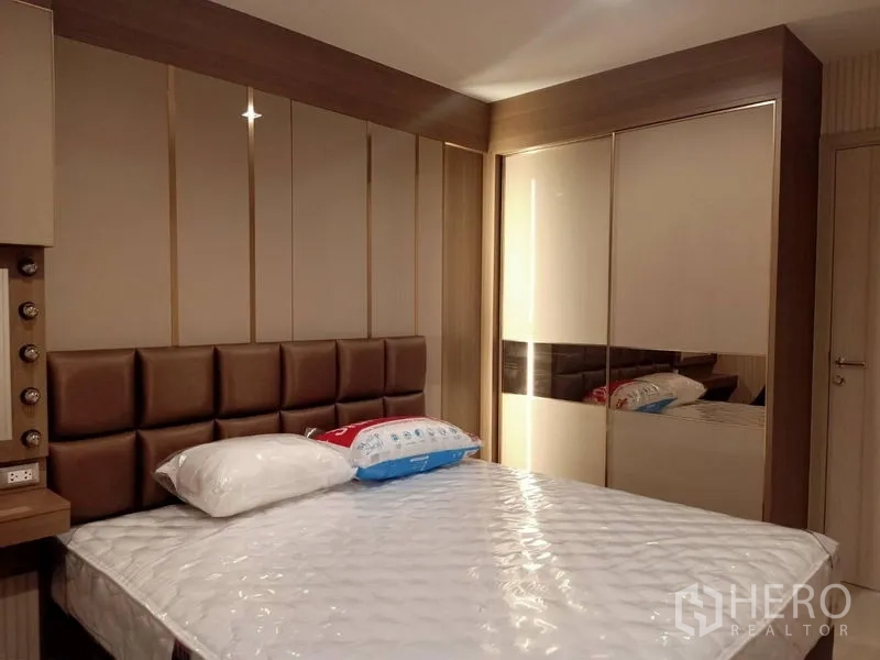 Condominium for rent in Pathum Wan, Bangkok - Master bedroom with padded headboard, vanity and mirrored wardrobe.