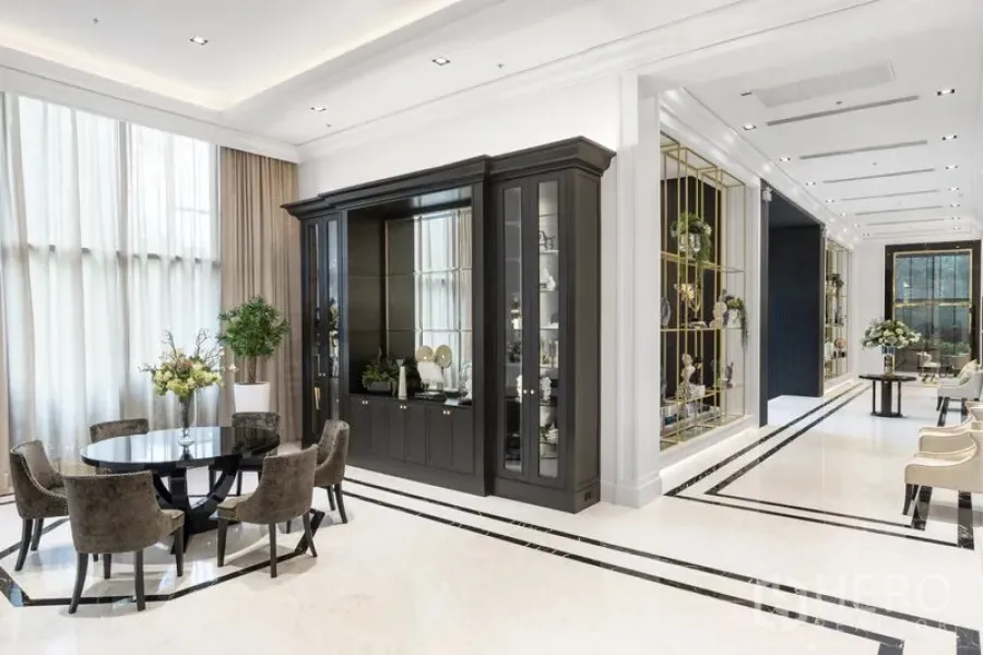 Condominium for rent in Pathum Wan, Bangkok - Bright, elegant condo lobby with a round dining table, tall curtains, and a dark built-in cabinet.
