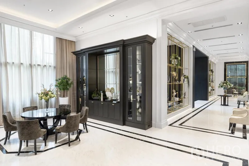 Condominium for rent in Pathum Wan, Bangkok - Bright, elegant condo lobby with a round dining table, tall curtains, and a dark built-in cabinet.