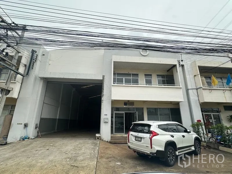 Factory for rent in Khlong Luang, Pathum Thani - Exterior view showing parking space and overhead power lines at the front.