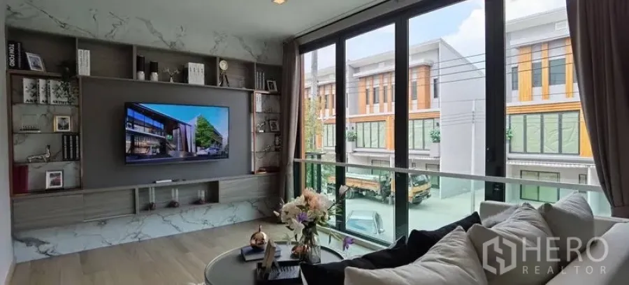 联排别墅 出租在Prawet, Bangkok - 二楼会客区，仿大理石背景墙与壁柜，落地推拉门俯瞰联排景致。