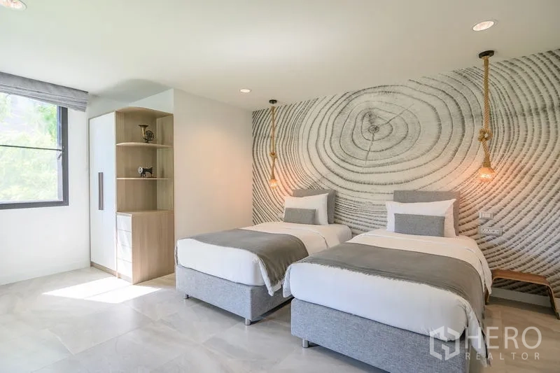Condominium for rent in Pathum Wan, Bangkok - Bright twin bedroom with tree-ring mural, rope pendant lights, and large window.