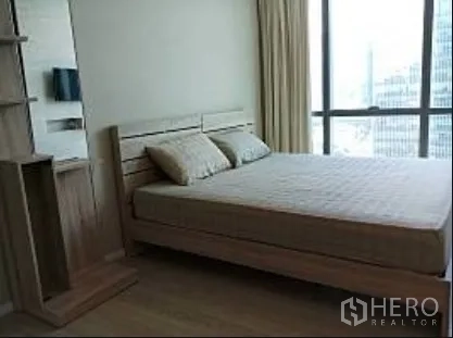 公寓 出租在Watthana, Bangkok - 卧室配大床与浅木色家具，靠窗可观曼谷城景。