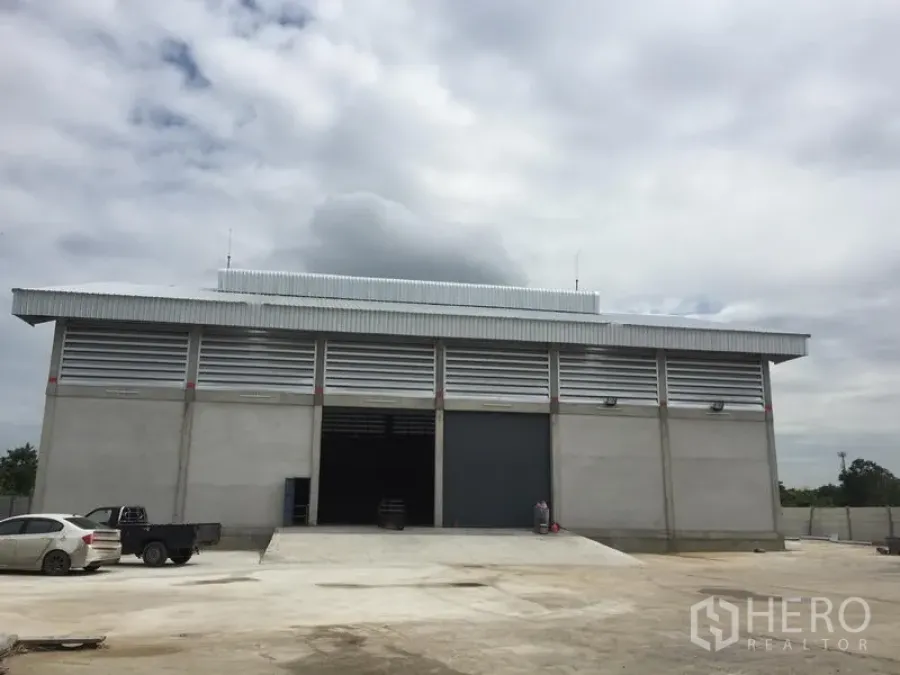 货栈 出租在Khlong Sam Wa, Bangkok - 仓库外立面，混凝土结构，超宽卷闸门、装卸坡道与大进出场地。