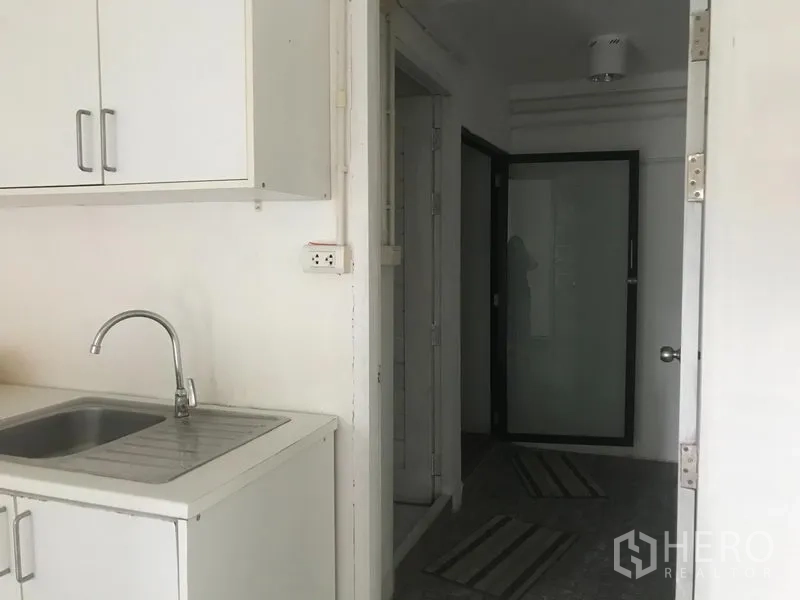 อาคารพาณิชย์ ให้เช่าในWatthana, Bangkok - แพนทรีตู้บิวท์อินสีขาวพร้อมอ่างล้างจาน ถัดไปเป็นทางเดินและประตูกระจกฝ้า