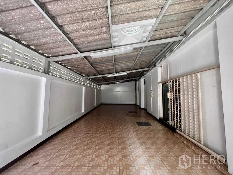 Shophouse for rent in Khlong San, Bangkok - Covered side corridor with tiled floor, metal roof and utility access.