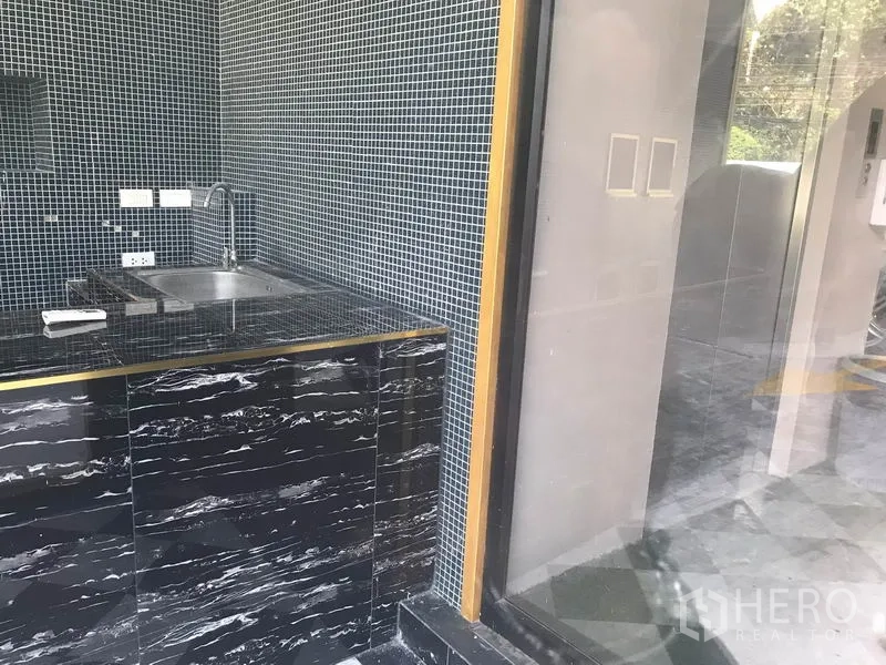 零售空间 出租在Watthana, Bangkok - 靠近玻璃入口的不锈钢水槽与黑色台面细节。