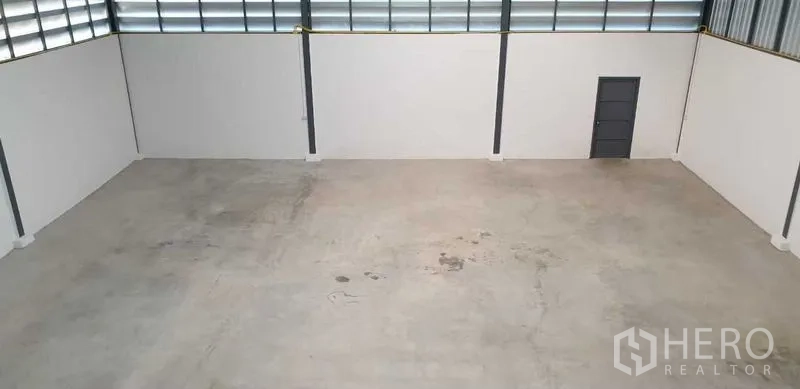 Factory for rent in Lam Luk Ka, Pathum Thani - Empty warehouse floor with smooth concrete surface and high white walls.