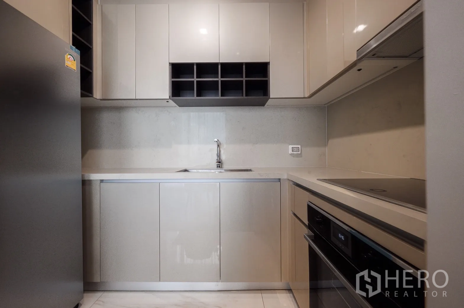 Condominium for rent or sale in Watthana, Bangkok - Modern fitted kitchen with glossy cabinets, built-in oven, electric cooktop and ample storage.