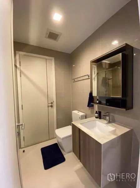 公寓 出租或出售在Phaya Thai, Bangkok - 现代卫浴，含洗手台、镜柜与马桶，色调素雅。