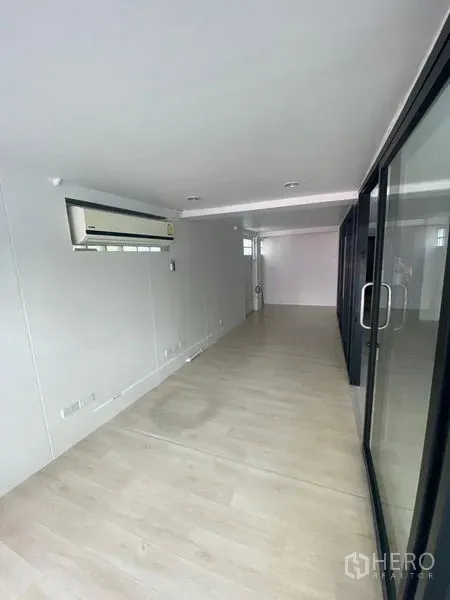 พื้นที่ขายปลีก ให้เช่าในWatthana, Bangkok - ภายในร้านทรงลึก พื้นไม้ลามิเนต ผนังสีขาว ไฟดาวน์ไลท์ ประตูกระจกบานเลื่อน และแอร์แขวนผนัง