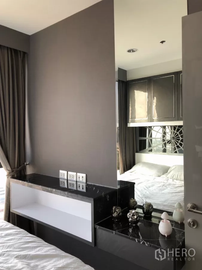 Condominium for rent in Khlong Toei, Bangkok - Bedroom corner with black marble vanity, mirror and overhead cabinets.