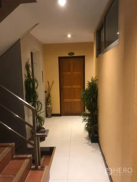 店屋 出租在Bang Rak, Bangkok - 室内走廊，楼梯与绿植通向木门。