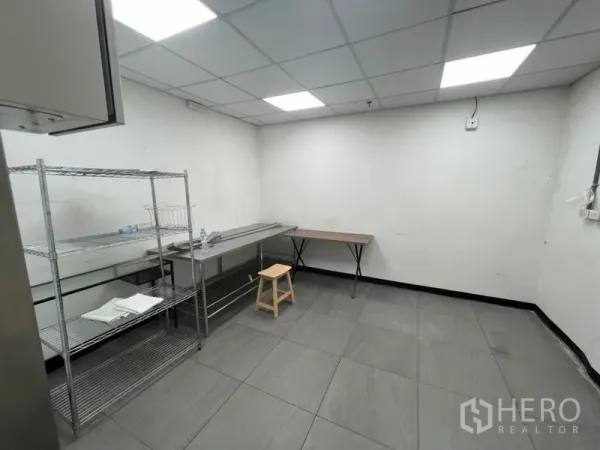 Retail Space for rent in Watthana, Bangkok - Back-of-house prep room with tiled floor, drop ceiling lights, stainless shelving and worktables inside Sukhumvit retail space.