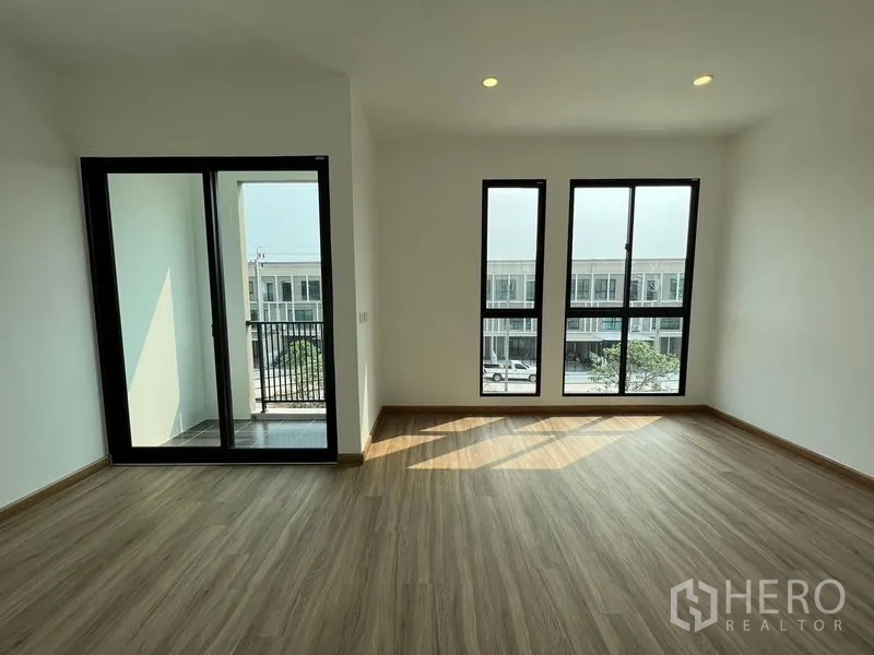Townhouse for rent in Bang Kapi, Bangkok - Corner bedroom with balcony access and twin vertical windows.
