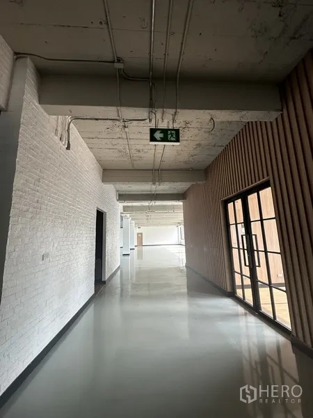 Office Space for rent - Bright hallway with white brick wall and emergency exit sign.