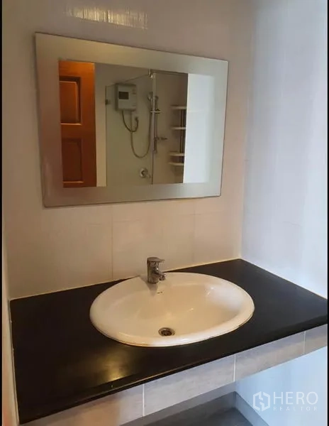Condominium for rent in Ratchathewi, Bangkok - Vanity with round basin, black countertop and large mirror.