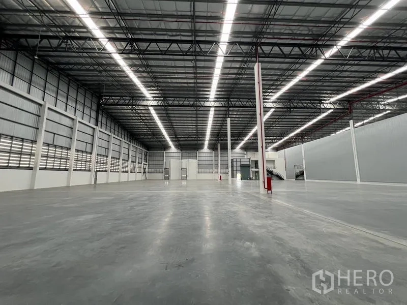 Warehouse for rent in Chon Buri - Symmetrical view of the warehouse hall with concrete slab and evenly spaced columns.