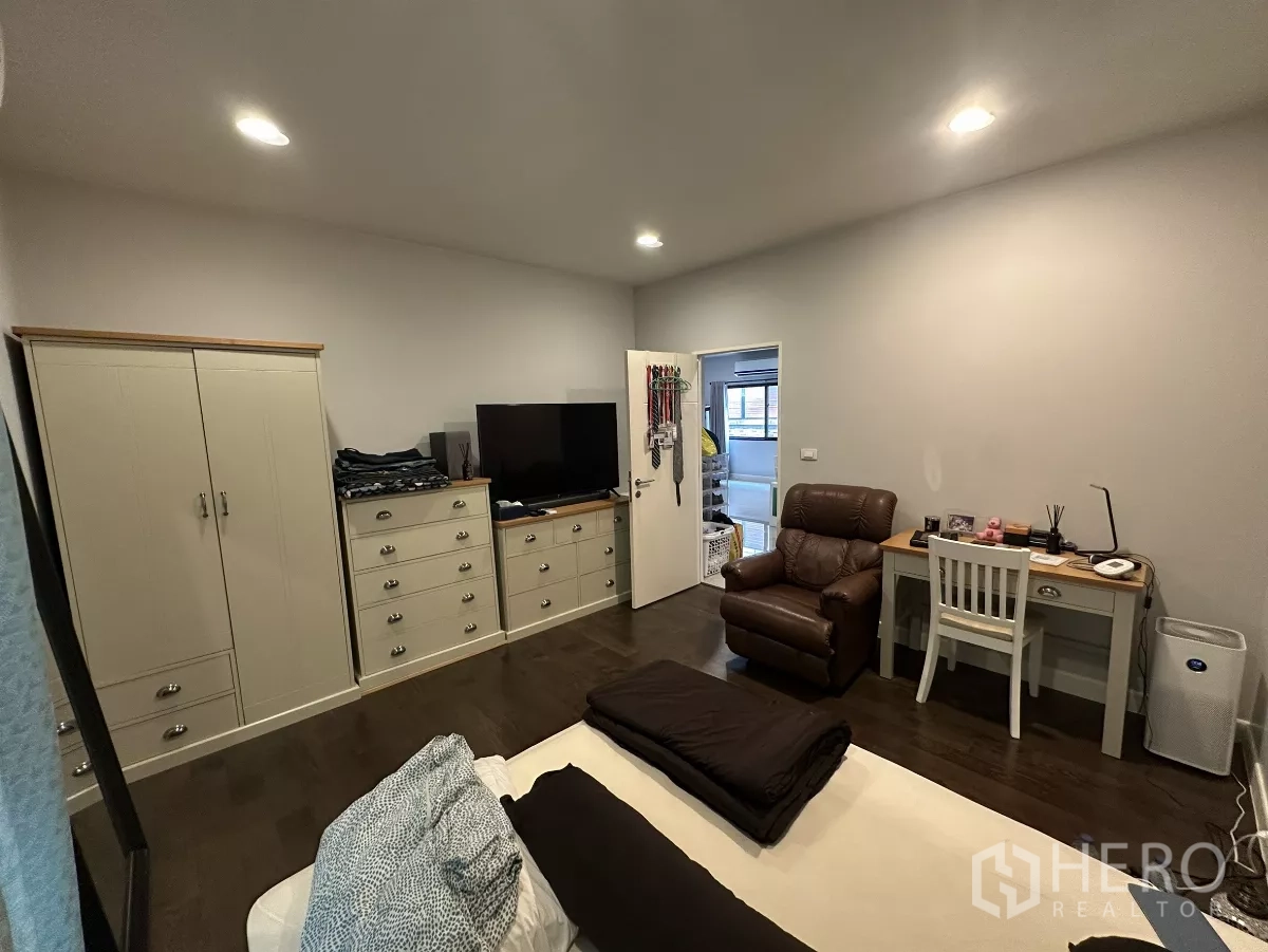 บ้าน ให้เช่าหรือขายในLam Luk Ka, Pathum Thani - ห้องนอนอบอุ่น มีเตียง ตู้เสื้อผ้า ชั้นวางทีวี โต๊ะทำงาน และเก้าอี้เอน