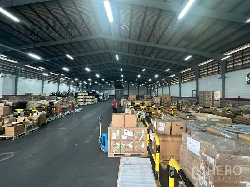 คลังสินค้า ให้เช่าในKhlong Toei, Bangkok - ทางเดินโกดังกว้าง ใต้โครงหลังคาเหล็ก พร้อมพาเลทและลังสินค้าวางอย่างเป็นระเบียบ.