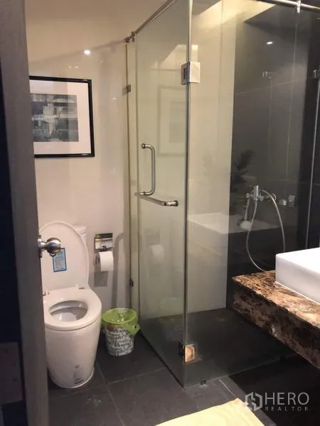 Condominium for rent in Pathum Wan, Bangkok - Modern bathroom featuring a glass-enclosed shower next to the toilet.