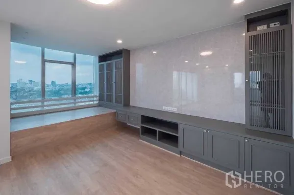 คอนโด ขายในChatuchak, Bangkok - พื้นที่นั่งเล่นพร้อมตู้บิลท์อินสีเทา เวทีนั่งยกระดับ และหน้าต่างกระจกสูงวิวเมือง