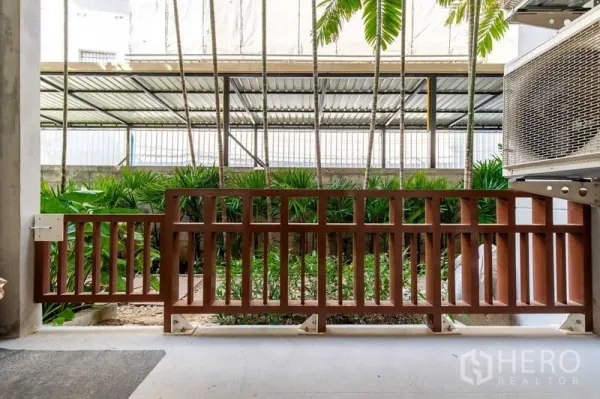 Condominium for rent in Phra Khanong, Bangkok - Condo terrace with wooden railing overlooking a tropical garden in Khlong Toei, Bangkok.