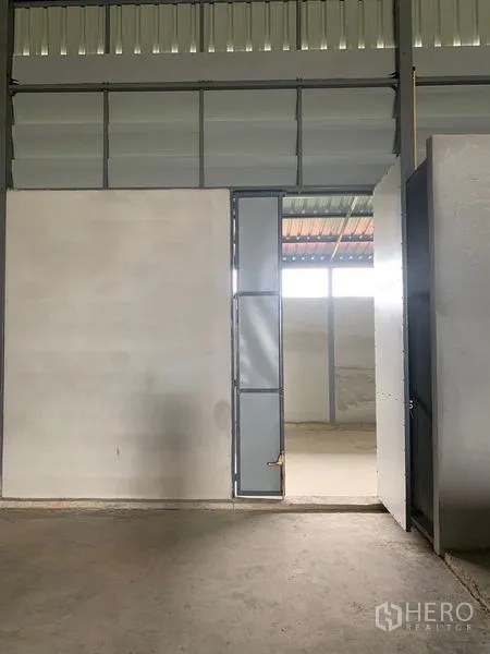 Warehouse for rent or sale in Sai Noi, Nonthaburi - Interior steel personnel door and high ventilation louvers inside the warehouse.