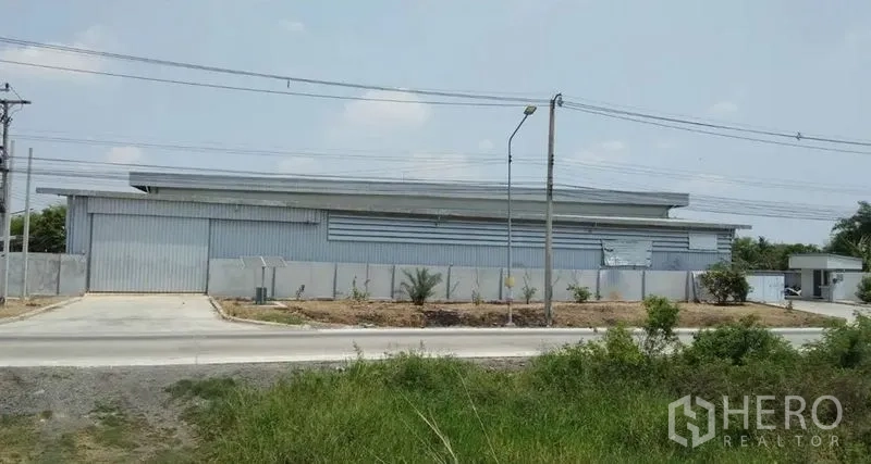 คลังสินค้า ให้เช่าในPathum Thani - มุมมองด้านข้างอาคารโกดัง ประตูทางเข้ากว้างและถนนคอนกรีต