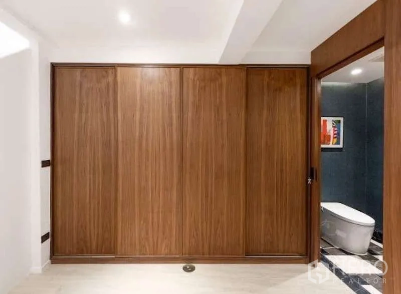 Townhouse for sale in Sathon, Bangkok - Room with full-height wooden wardrobes and sliding door to an ensuite bathroom.