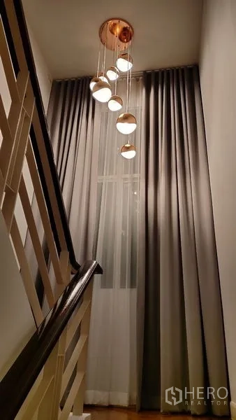 独立式住宅 出租在Prawet, Bangkok - 楼梯间，垂坠吊灯与通高窗帘