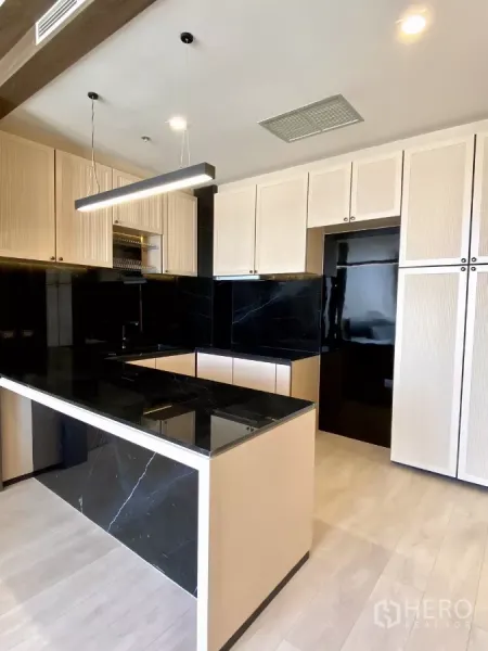 คอนโด ขายในPathum Wan, Bangkok - ครัวสไตล์โมเดิร์น เคาน์เตอร์ไอส์แลนด์หินสีดำ ตู้ไม้โทนอ่อนและโคมแขวน