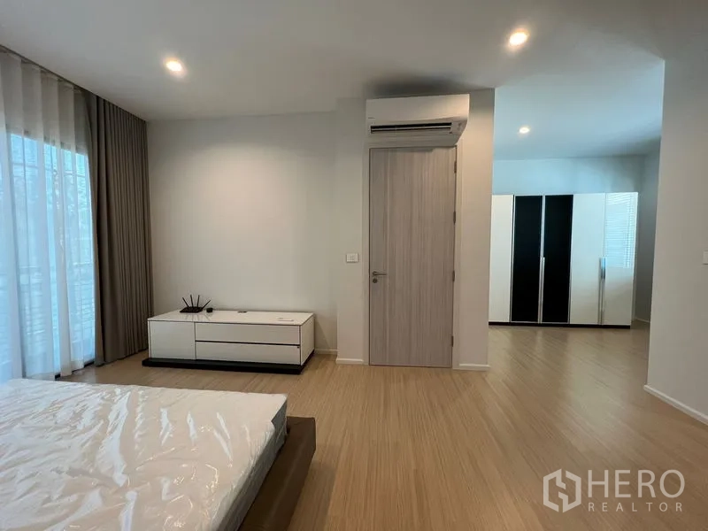 Townhouse for rent in Suan Luang, Bangkok - Master bedroom showing wood floors, air-conditioning and access to the wardrobe area.