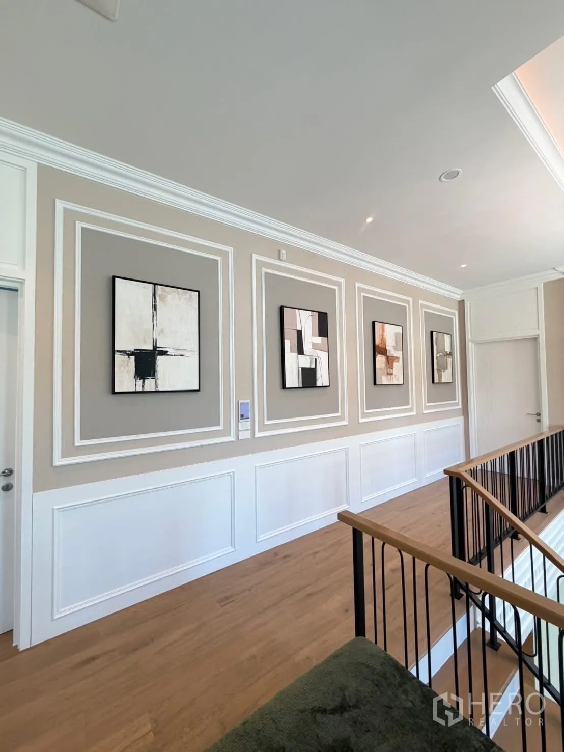 Detached House for rent in Saphan Sung, Bangkok - Hallway gallery with framed abstract art and wood floors along the staircase.