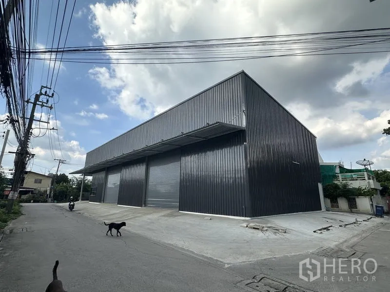 คลังสินค้า ให้เช่าในBang Kapi, Bangkok - มุมมองโกดังผนังเมทัลชีทใหม่ พร้อมประตูม้วนหลายบานและทางลาดขนถ่ายสินค้าในเขตบางกะปิ