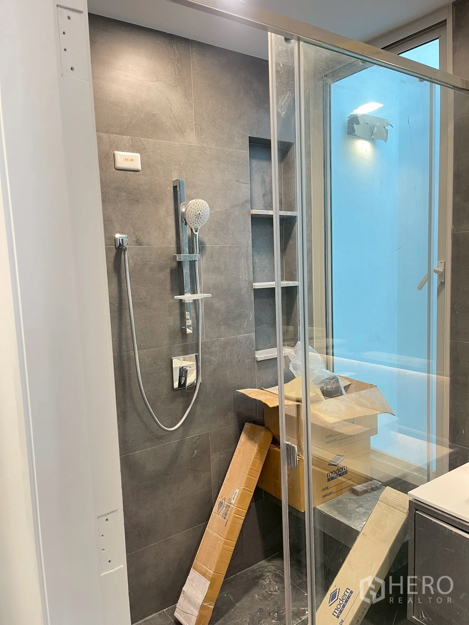Detached House for sale in Bang Phli, Samut Prakan - Bathroom with gray tiles and glass shower enclosure being fitted.