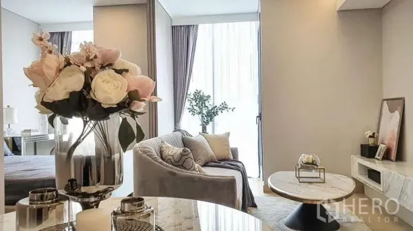 Condominium for sale in Khlong Toei, Bangkok - View from dining table with flower arrangement toward bright living area and bedroom in neutral tones.