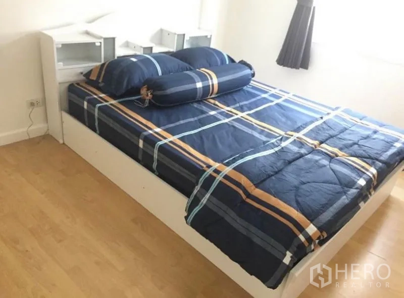 联排别墅 出租在Prawet, Bangkok - 温馨卧室，白色床架，海军蓝格纹床品，床头收纳与窗户。