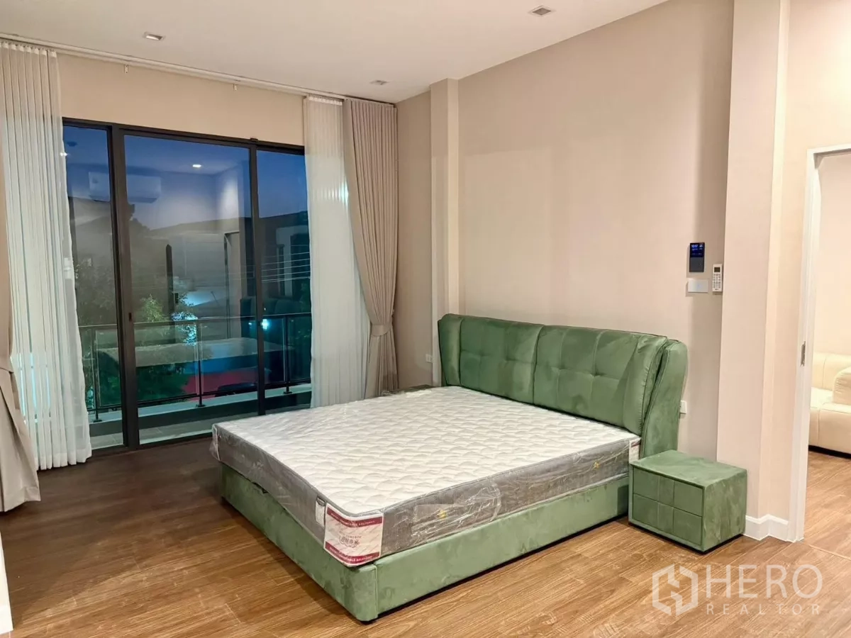 Detached House for rent in Bang Phli, Samut Prakan - Master bedroom with upholstered green bed and access to a balcony.