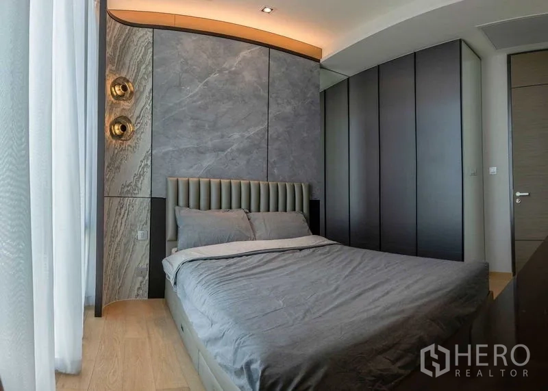 Condominium for rent - Second bedroom with upholstered headboard, stone accent wall and full-height wardrobes.