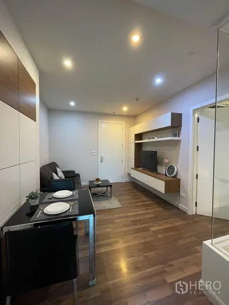 คอนโด ให้เช่าหรือขายในPhra Khanong, Bangkok - ห้องนั่งเล่นโทนอบอุ่น พื้นไม้ ตู้ทีวีลอย โต๊ะทานอาหารสำหรับสอง และไฟฝัง