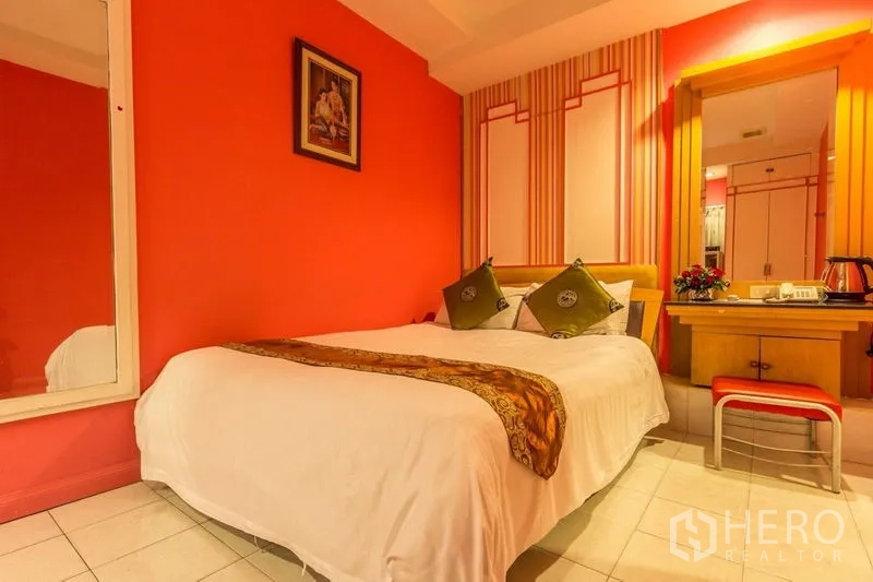 店屋 出租在Phaya Thai, Bangkok - 红色主题卧室，床侧书桌与装饰抱枕。