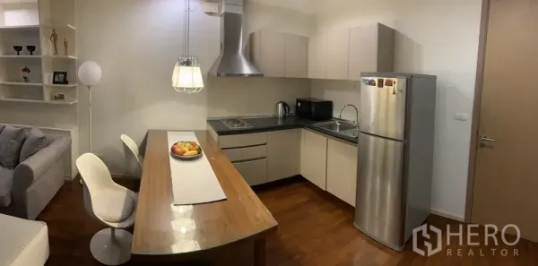 คอนโด ให้เช่าหรือขายในKhlong Toei, Bangkok - ครัวรูปตัวแอลสมัยใหม่ ตู้เก็บของบนล่าง ตู้เย็นและฮูดสแตนเลส พร้อมโต๊ะทานข้าวไม้สำหรับสองที่