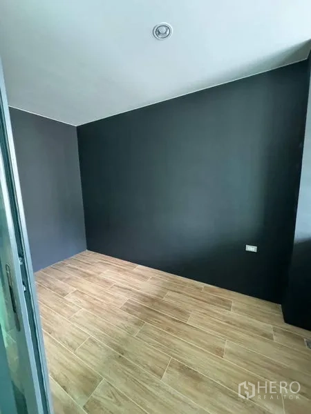 Townhouse for rent - Compact bedroom or study with wood-look flooring and dark accent wall.
