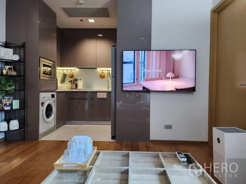 公寓 出租在Watthana, Bangkok - 开放式客厅连接亮面L型厨房与壁挂电视。