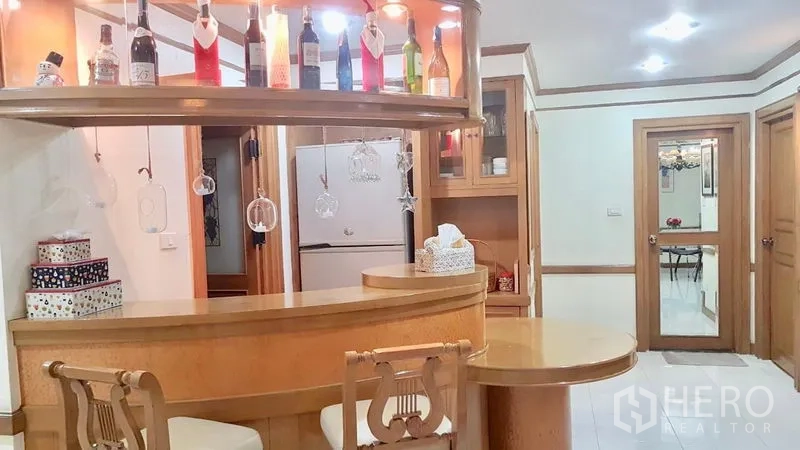 คอนโด ให้เช่าในWatthana, Bangkok - เคาน์เตอร์บาร์โค้งพร้อมชั้นแขวนแก้ว เก้าอี้สตูล และมุมมองไปยังครัว