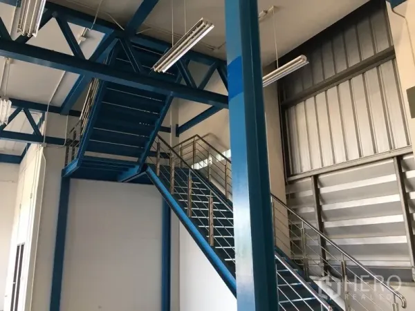 คลังสินค้า ให้เช่าในLat Krabang, Bangkok - พื้นที่ชั้นลอยภายในพร้อมบันไดเหล็กสีน้ำเงินและไฟฟลูออเรสเซนต์ในอาคารอุตสาหกรรม
