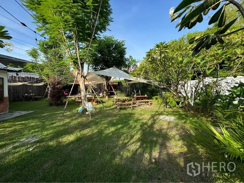 Land for rent in Bang Na, Bangkok - Shaded garden area on the plot with picnic tables, canopy sails, and string lights.