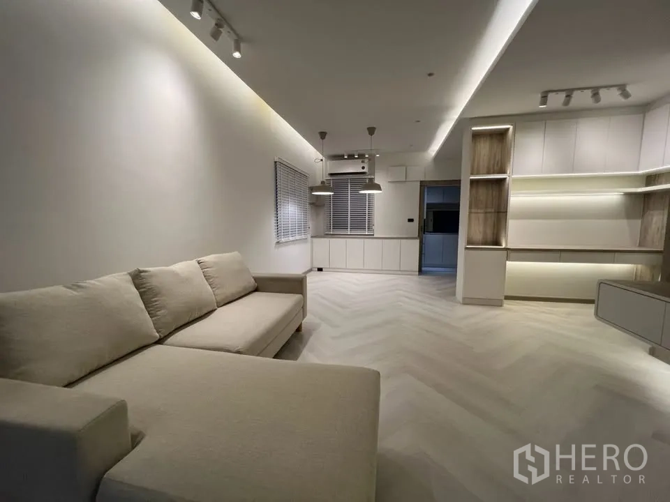 Townhouse for rent in Prawet, Bangkok - Lounge area with sectional sofa and illuminated shelving.